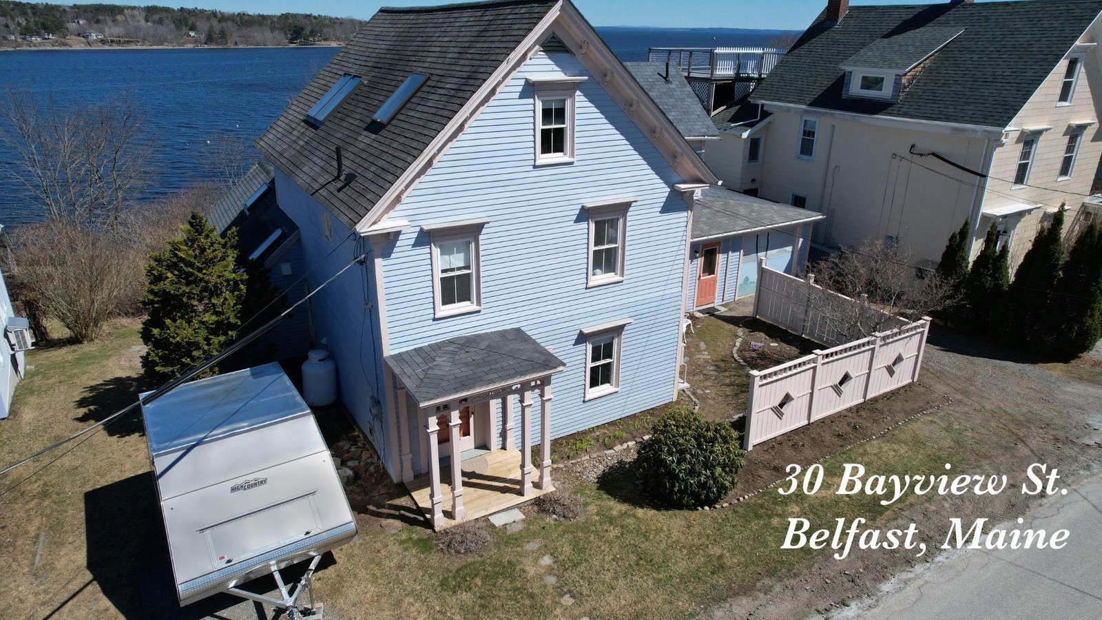 Aerial drone view of a waterfront home at 30 Bayview Street in Belfast, Maine with bay views and neighboring properties.