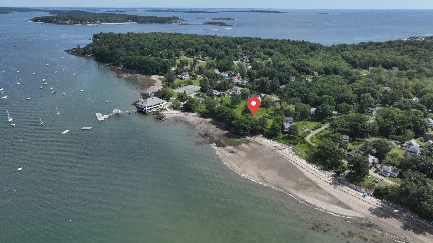 Aerial drone photograph of waterfront land with a location marker