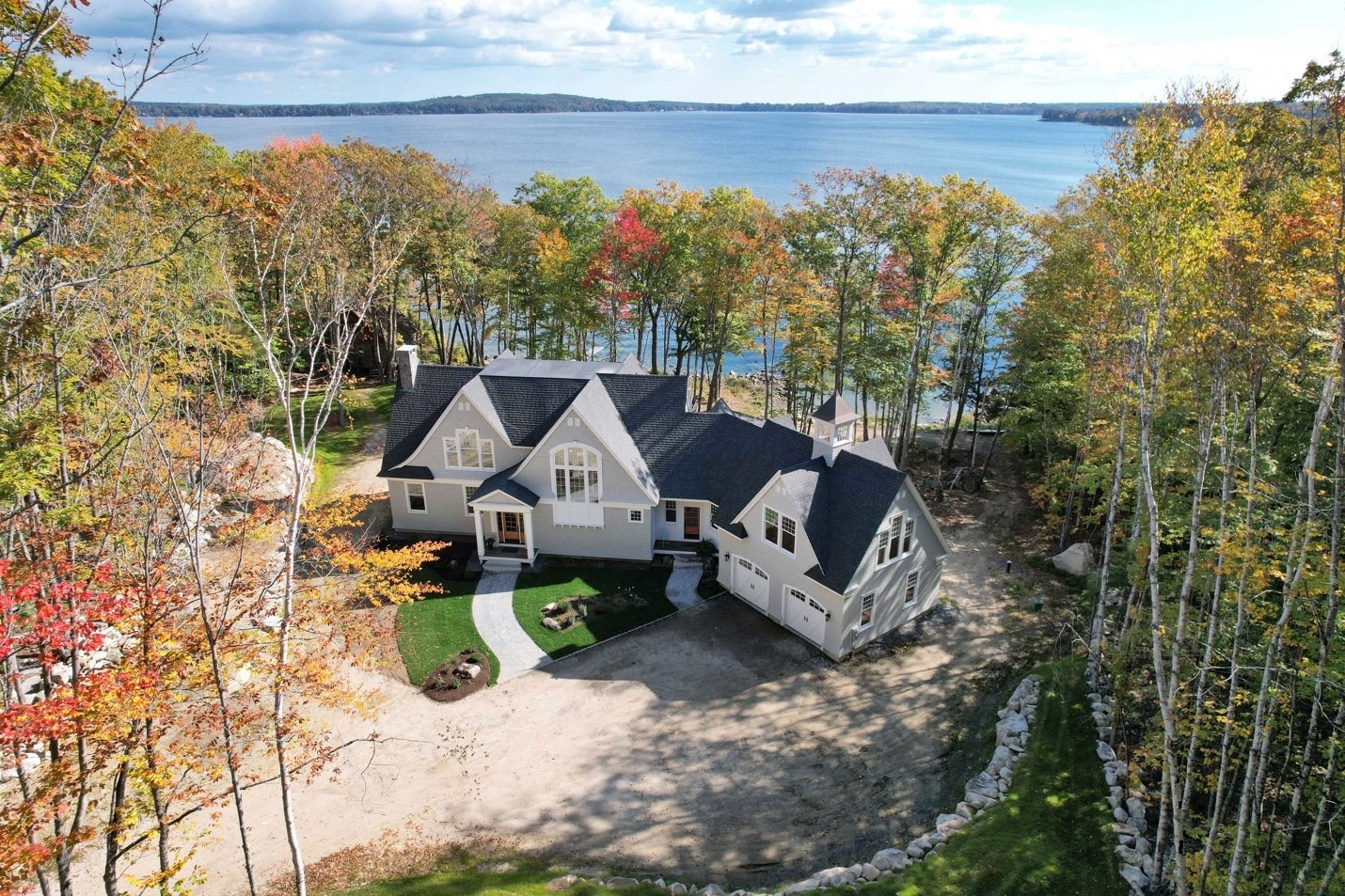 Aerial view of a house in Windham, Maine, surrounded by trees with water visible behind the property